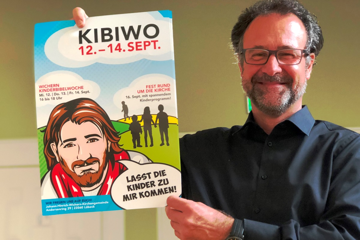 Pastor Christian Gauer mit dem Plakat zur Kinderbibelwoche 2018.
